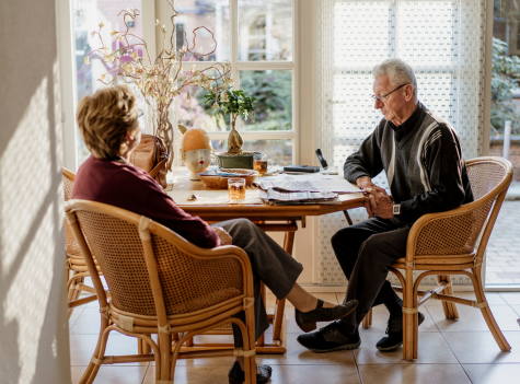 Elderly Couple At The Table Reading A Newspaper