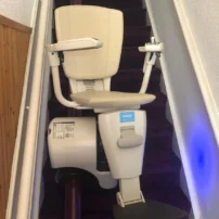 a beige stairlift on dark stairs